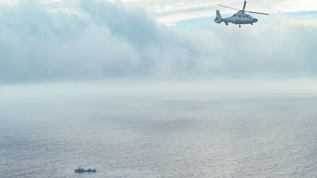 Un appareil identifié par les garde-côtes philippins comme étant un hélicoptère de la marine chinoise (à gauche) vole près de l'avion du Bureau des pêches et des ressources aquatiques (BFAR) lors d'un vol de reconnaissance aérienne sur le haut-fond de Scarborough, en mer de Chine méridionale, le 18 février 2025.