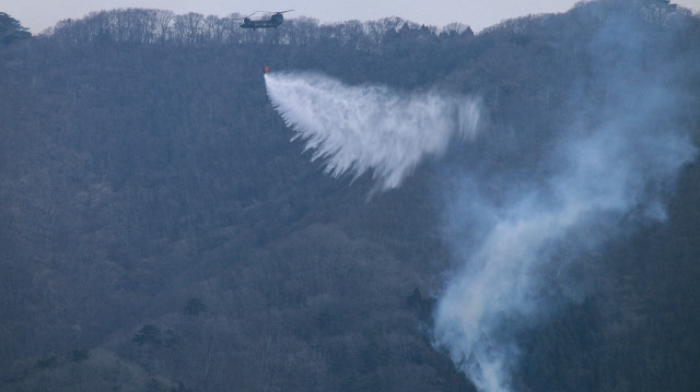 Cette photo prise le 1er mars 2025 et reçue par l'AFP du ministère japonais de la Défense le 3 mars 2025 montre un hélicoptère de la Force d'autodéfense terrestre larguant de l'eau alors qu'ils combattent un feu de forêt près de la ville d'Ofunato, dans la préfecture d'Iwate.
