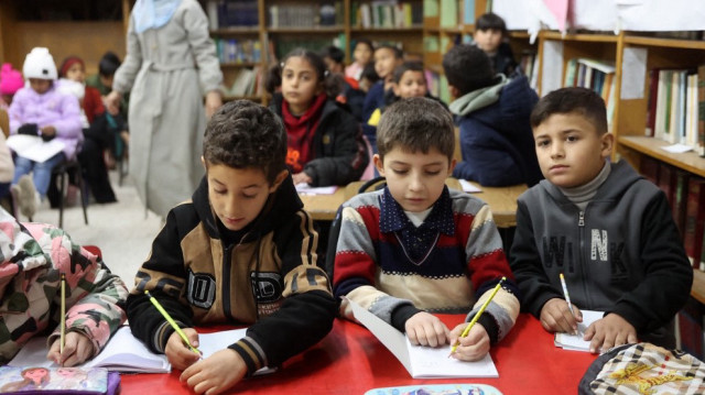 Des élèves palestiniens écrivent dans leurs cahiers lors du premier jour de classe dans une école de la ville de Gaza, le 23 février 2025.