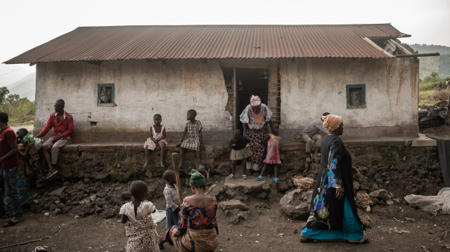 Kimoka (à droite), une femme qui a reçu une balle dans la joue alors qu'elle tentait de nettoyer sa parcelle et de brûler les ordures, marche dans sa maison de Sake le 27 février 2025.