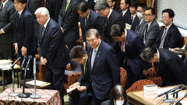 Le Premier ministre japonais Shigeru Ishiba (C) et d'autres personnes s'inclinent après l'adoption par la chambre basse du parlement de l'amendement du parti au projet de loi de finances pour l'exercice 2025, à Tokyo, le 4 mars 2025.