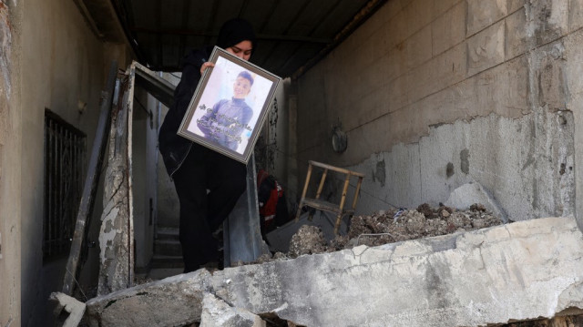 Une femme récupère une photo encadrée alors qu'elle s'apprête à quitter le camp de réfugiés palestiniens de Nur Shams.