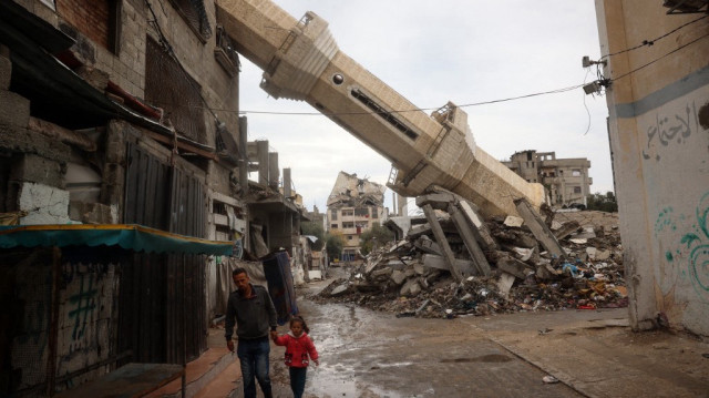 Un Palestinien accompagné d'un enfant marche près d'un minaret tombé d'une mosquée détruite pendant le mois de jeûne musulman du Ramadan, dans le centre de la bande de Gaza, le 7 mars 2025.