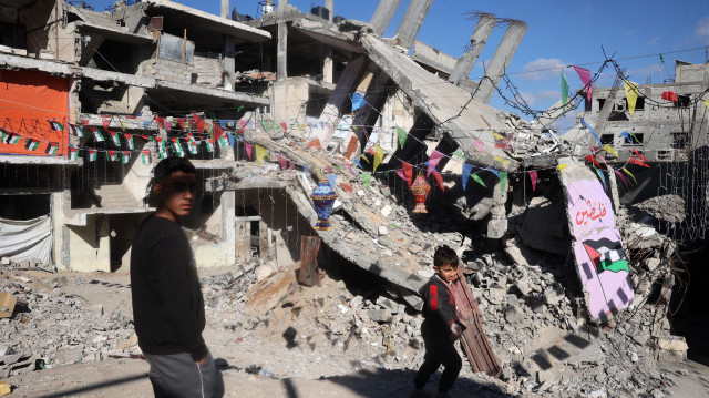De jeunes Palestiniens marchent dans un quartier dévasté par la guerre, décoré à l'approche du mois de jeûne musulman du Ramadan, à Khan Yunis, dans le sud de la bande de Gaza, le 28 février 2025, alors qu'un cessez-le-feu est en cours dans la guerre entre Israël et le Hamas.