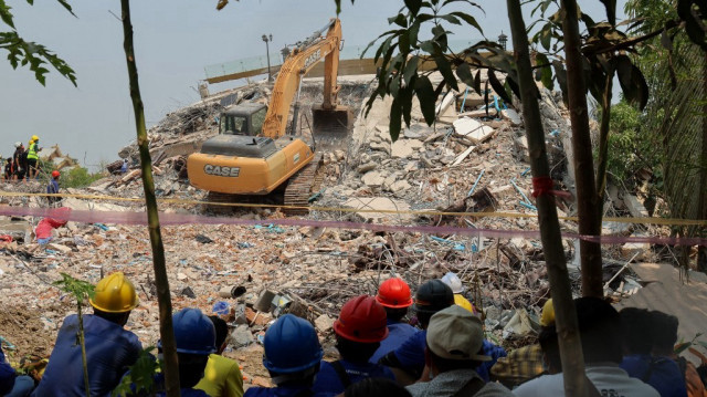 Les secouristes observent l'utilisation de gros équipements de construction pour rechercher des personnes coincées sous les décombres du développement du Sky Villa Condominium à Mandalay, le 1er avril 2025.