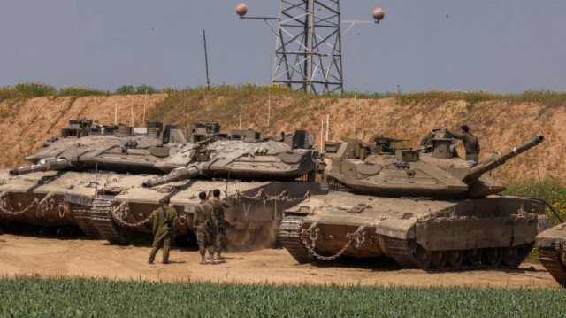 Un soldat de l'armée israélienne fait signe au conducteur d'un char de combat Merkava qui tente de se garer sur une position dans le sud d'Israël, le long du nord de la bande de Gaza, le 18 mars 2025.