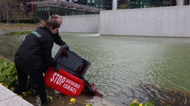 Une photo diffusée par le groupe d'action environnementale Greenpeace UK le 10 avril 2025 montre des militants de Greenpeace UK versant 300 litres de colorant rouge sang dans l'étang de l'ambassade des États-Unis à Londres le 10 avril 2025, alors qu'ils demandent aux gouvernements britannique et américain d'imposer un embargo sur les armes à Israël, qui a renouvelé son offensive à Gaza le mois dernier.