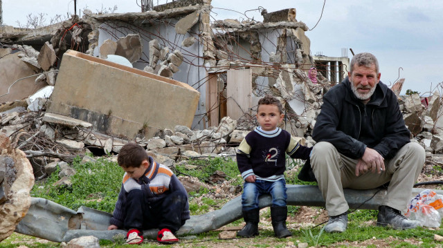 Les membres d'une famille sont assis devant leur maison détruite dans le village frontalier de Wazzani, au sud du Liban, le 19 février 2025.