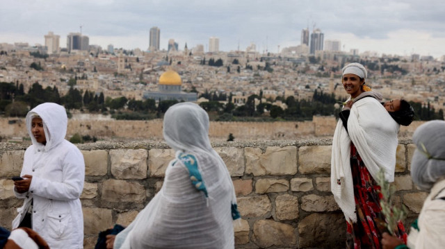 Des fidèles chrétiens marchent sur une route surplombant le complexe de la mosquée al-Aqsa, lors de la procession traditionnelle du dimanche des Rameaux au Mont des Oliviers à Jérusalem, le 13 avril 2025.