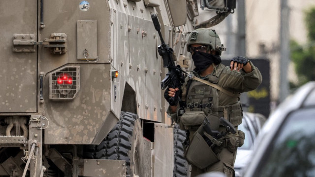 Un soldat de l'armée israélienne se tient devant un véhicule blindé lors d'une opération militaire israélienne à Naplouse, en Palestine occupée, le 8 avril 2025.