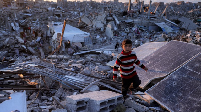Un garçon passe devant des panneaux solaires cassés au milieu des décombres à Jabalia, dans le nord de la bande de Gaza, le 14 avril 2025.