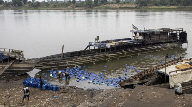 Vue générale d'un bateau en provenance de la République démocratique du Congo (RDC) déchargeant des bouteilles de gaz sur le fleuve Ubangui à Bangui le 5 mars 2025.