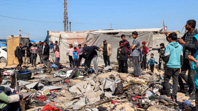 Des enfants se rassemblent tandis qu'un homme inspecte les restes d'un abri de tente qui aurait été touché par une frappe israélienne à Khan Yunis, dans le sud de la bande de Gaza, le 17 avril 2025.