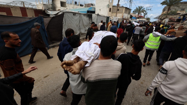 Des Palestiniens transportent le corps d'une personne tuée lors d'une frappe israélienne vers l'hôpital des Martyrs d'al-Aqsa à Deir el-Balah, dans le centre de la bande de Gaza, le 13 avril 2025.