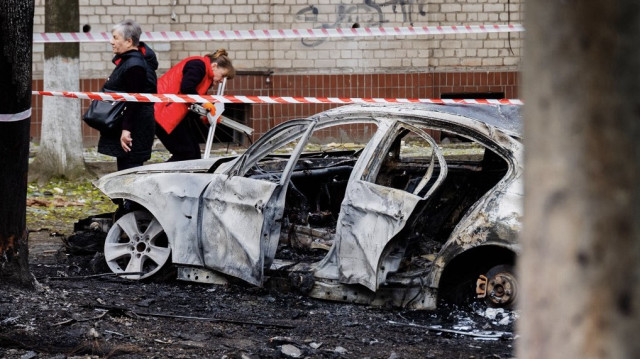 Cette photo prise et diffusée par l'administration militaire régionale de Dnipropetrovsk le 17 avril 2025 montre des habitants à côté d'une voiture brûlée dans la cour d'un immeuble résidentiel après une attaque de drone à Dnipro, dans le cadre de l'invasion russe de l'Ukraine.