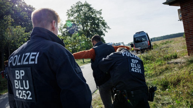 Des agents de la police fédérale allemande (Bundespolizei) contrôlent un migrant près de Forst, dans l'est de l'Allemagne, le 11 octobre 2023, lors d'une patrouille près de la frontière avec la Pologne.
