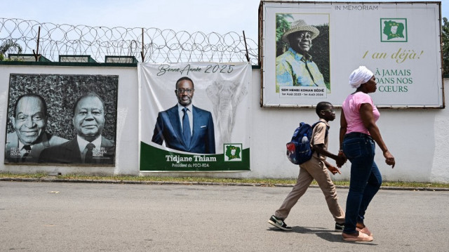 Des piétons passent devant une image de l'homme d'affaires ivoirien Tidjane Thiam à Abidjan le 16 avril 2025, alors que le principal parti d'opposition ivoirien, le Parti démocratique de Côte d'Ivoire (PDCI), s'apprête à le désigner comme candidat à l'élection présidentielle d'octobre 2025.