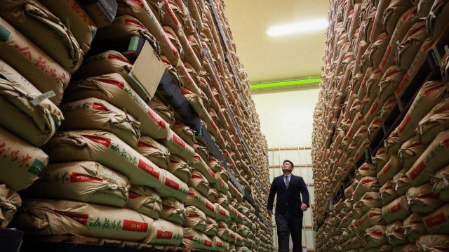 Un homme passant devant des sacs de riz stockés par le gouvernement dans un entrepôt de la préfecture de Saitama, au nord de Tokyo.