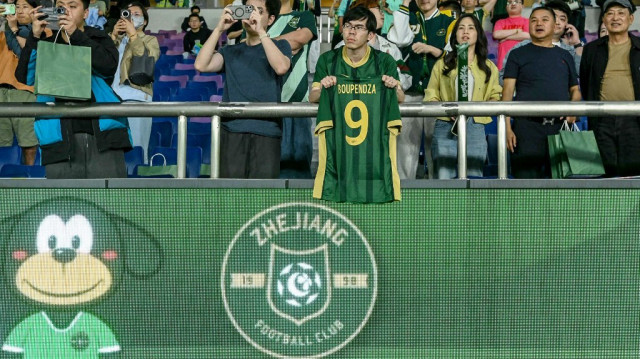 Un supporter brandit un maillot floqué au nom et au numéro de l’attaquant international gabonais Aaron Boupendza lors du match de Super League chinoise opposant le Zhejiang FC à Meizhou Hakka, à Hangzhou, dans la province orientale du Zhejiang, le 16 avril 2025.