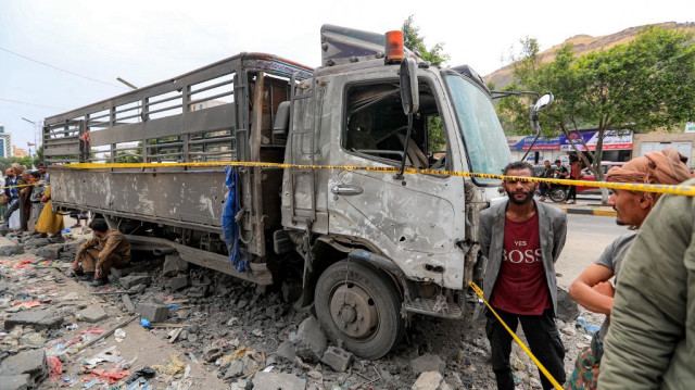 Des personnes se rassemblent près d'un véhicule endommagé sur le site d'une attaque aérienne américaine à Sanaa, la capitale du Yémen tenue par les Huthis, le 24 mars 2025.