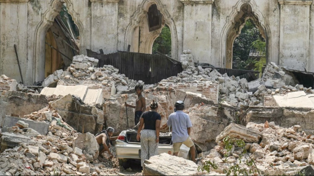 Des personnes dégagent une voiture des décombres d'un bâtiment détruit dans la banlieue de Mandalay, le 2 avril 2025, cinq jours après qu'un important tremblement de terre a frappé le centre du Myanmar.
