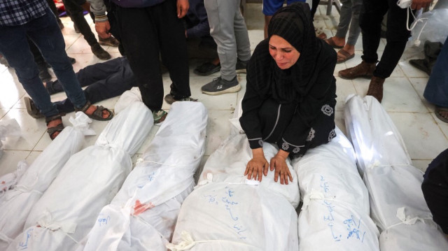 Une femme pleure les corps enveloppés de leurs proches tués lors d'une frappe israélienne qui a visé une clinique de l'ONU dans le camp de réfugiés palestiniens de Jabalia, dans le nord de la bande de Gaza, le 2 avril 2025.