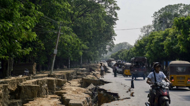 Des automobilistes passent devant une grande fissure dans le sol le long de la route Myo Patt reliant Mandalay et le canton de Sagaing, à la périphérie de Mandalay, le 2 avril 2025, cinq jours après qu'un important tremblement de terre a frappé le centre du Myanmar.