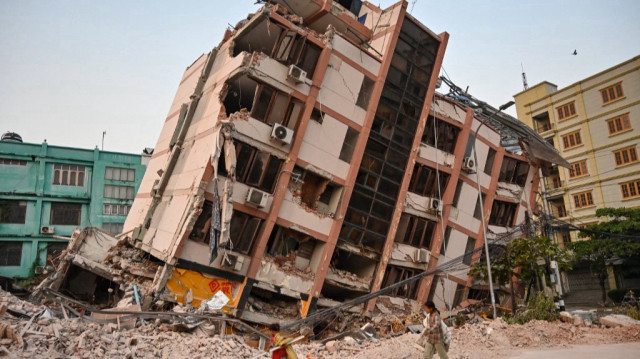 Des enfants passent devant un bâtiment effondré à Mandalay le 2 avril 2025, cinq jours après qu'un important tremblement de terre a frappé le centre du Myanmar.