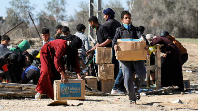 Un garçon marche avec un colis d'aide humanitaire fourni par l'Office de secours et de travaux des Nations Unies pour les réfugiés de Palestine (UNRWA) à al-Shoka, à l'est de Rafah dans le sud de la bande de Gaza, le 21 janvier 2025, à la suite d'un accord de cessez-le-feu dans la guerre entre Israël et le Hamas dans le territoire palestinien.