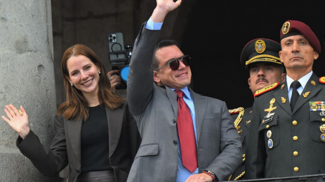 Le président réélu de l'Équateur, Daniel Noboa (C), salue ses partisans en compagnie de son épouse, Lavinia Valbonesi (G), et du chef de la Maison militaire présidentielle, Milton Rodriguez, depuis un balcon du palais présidentiel de Carondelet, lors de la cérémonie de relève de la garde à Quito, le 15 avril 2025.