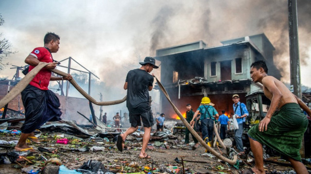 Des personnes éteignent un incendie dans un bâtiment qui a été détruit lors d'un bombardement effectué par l'armée du Myanmar dans le canton de Thabeikkyin, dans la région de Mandalay, au centre du Myanmar, le 19 avril 2025.