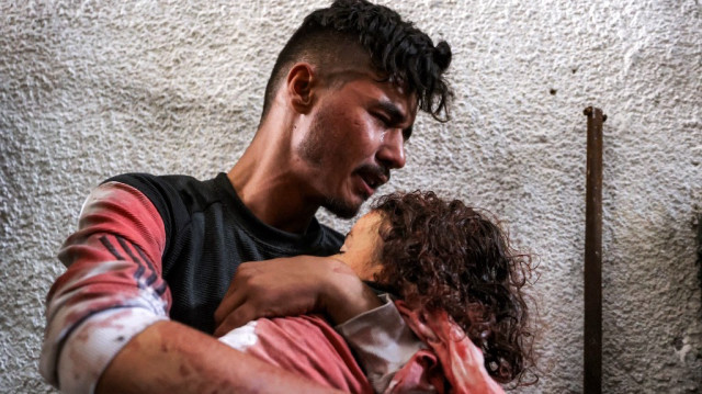 Le frère de Zain Hijazi, un enfant de quatre ans, tient son corps après que le garçon a été tué sur le site d'un campement de tentes pour les Palestiniens déplacés par le conflit qui a été touché par les bombardements israéliens au Jazira Club dans la ville de Gaza, le 21 avril 2025.