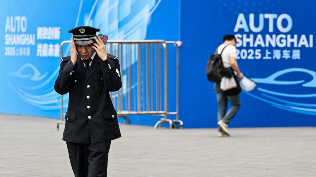 Un garde ajuste son chapeau à l'extérieur du National Exhibition and Convention Center, lieu de la 21e Exposition internationale de l'industrie automobile de Shanghai, à Shanghai le 21 avril 2025.