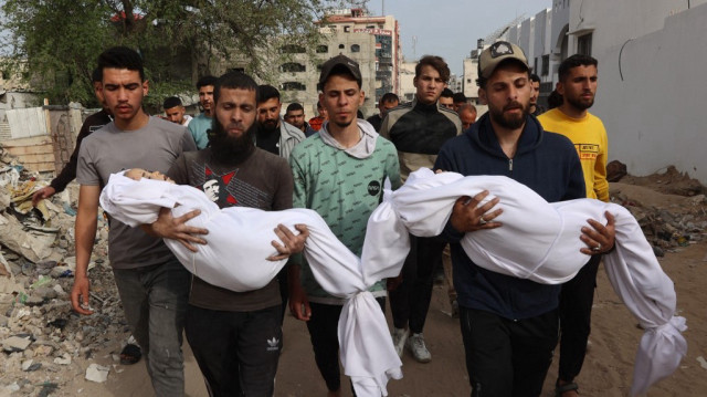 Des Palestiniens portent les corps enveloppés de membres de leur famille, tués lors d'une frappe israélienne sur une école transformée en abri, lors de leurs funérailles près de l'hôpital Al-Shifa dans la ville de Gaza, le 23 avril 2025.