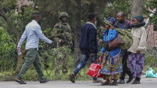 Un membre du groupe armé M23 se tient derrière des barbelés alors que des civils fuyant les affrontements en cours dans l'est de la République démocratique du Congo traversent la frontière avec le Rwanda au poste frontière de La Corniche à Gisenyi, le 29 janvier 2025.