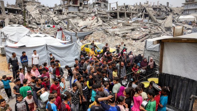 Des personnes font la queue avec des casseroles pour recevoir des repas de charité dans une cuisine à Beit Lahia, dans le nord de la bande de Gaza, le 24 avril 2025.
