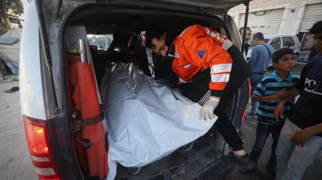 Paramedics and a local residents carry a lifeless body from the rubble of a building after an Israeli attack on a school in the Yarmouk camp in northern Gaza on April 25, 2025. The Israeli attack resulted in multiple casualties, and emergency teams continued their rescue efforts at the site.(AA)