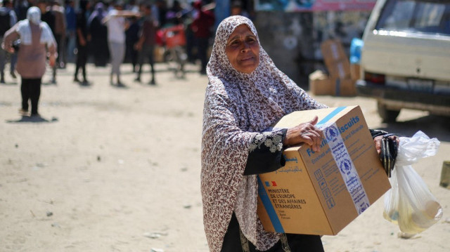 Des Palestiniens reçoivent des colis alimentaires d'un centre de distribution du Programme alimentaire mondial (PAM) des Nations unies dans le camp de réfugiés de Nuseirat, au centre de la bande de Gaza, le 26 avril 2025.
