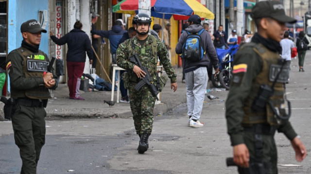 Des policiers colombiens et un soldat patrouillent dans le quartier de San Bernardo près du site de l'explosion d'une grenade à Bogota le 13 mars 2025.