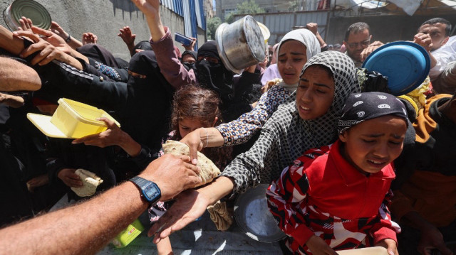 Des Palestiniens font la queue pour un repas chaud dans une cuisine de charité gérée par le Programme alimentaire mondial (PAM) des Nations unies dans le camp de réfugiés de Nuseirat, au centre de la bande de Gaza, le 26 avril 2025.