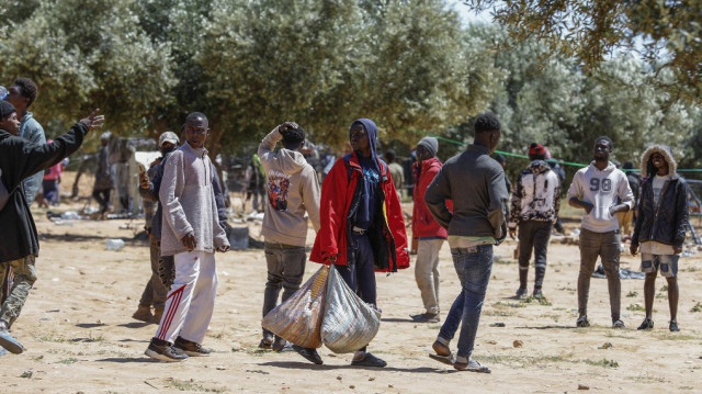 Des personnes quittent avec leurs affaires un camp de fortune pour migrants d'Afrique subsaharienne alors que les autorités démantèlent le camp à al-Amra, à la périphérie de la ville tunisienne de Sfax, le 24 avril 2025.