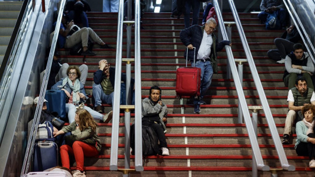 Des voyageurs s'assoient dans les escaliers alors qu'ils se préparent à passer la nuit à la gare d'Atocha, à la suite d'une coupure d'électricité massive affectant toute la péninsule ibérique et le sud de la France, à Madrid, le 28 avril 2025.
