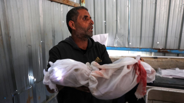 Un homme tient le corps d'un enfant tué lors d'une frappe israélienne qui a visé une clinique de l'ONU dans le camp de réfugiés palestiniens de Jabalia, à l'hôpital indonésien de Beit Lahia, dans le nord de la bande de Gaza, le 2 avril 2025.