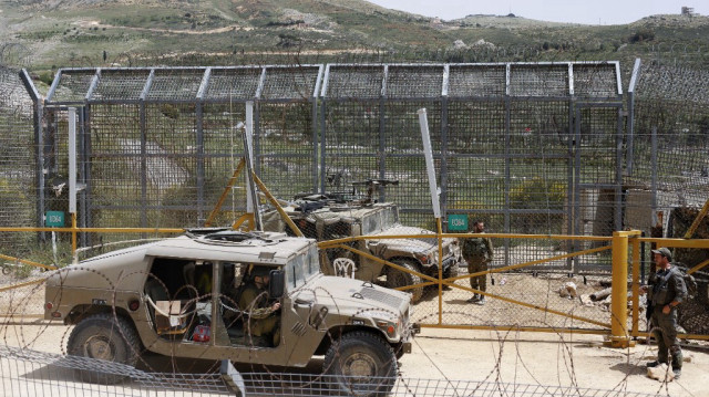 Des soldats israéliens montent la garde alors que des hommes druzes manifestent en solidarité avec la communauté druze syrienne près de la barrière frontalière dans le village de Majdal Shams sur le plateau du Golan annexé par Israël, le 30 avril 2025.