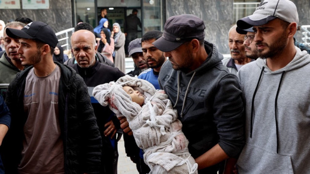Un homme porte le corps enveloppé de Farah Ahmed, qui a été tuée avec d'autres membres de sa famille lorsqu'une frappe israélienne a touché leur maison, alors qu'il marche à l'extérieur de l'hôpital Al-Awda dans le camp de réfugiés de Nuseirat, dans le centre de la bande de Gaza, le 30 avril 2025.