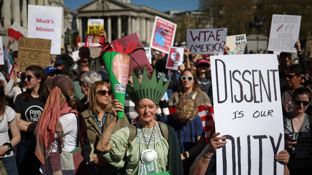 Des personnes brandissent des pancartes lors d'une manifestation contre le président américain Donald Trump et son conseiller principal Elon Musk dans le centre de Londres, le 5 avril 2025, dans le cadre d'une journée internationale de protestation intitulée "Hands off !" (Bas les pattes !). La campagne "Bas les pattes !" exige "la fin de ce coup de force des milliardaires".
