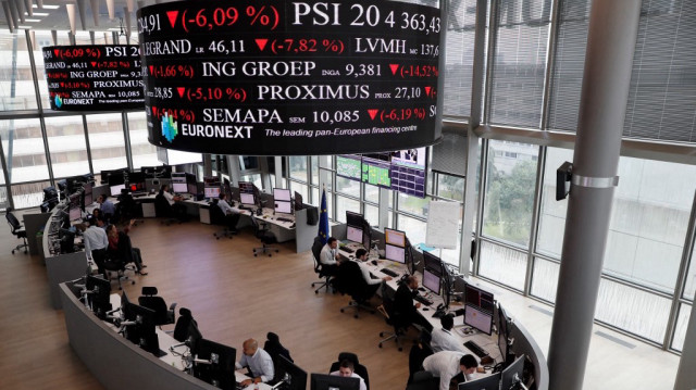 Des personnes travaillent sur des écrans affichant des nouvelles et des taux de négociation dans les services de la bourse Euronext dans le quartier financier de La Défense à Paris.