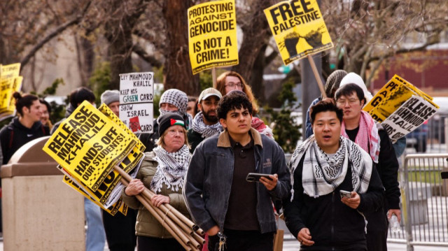 Des personnes brandissent des pancartes alors qu'elles arrivent à une manifestation de soutien à Mahmoud Khalil, étudiant activiste de l'Université de Columbia, pendant qu'une audience a lieu, devant le tribunal de Newark, New Jersey, le 28 mars 2025.