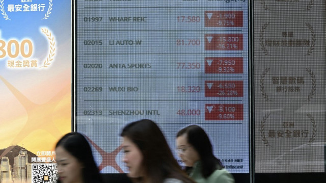Des personnes passent devant un panneau électronique indiquant l'indice Heng Seng à Hong Kong le 7 avril 2025.