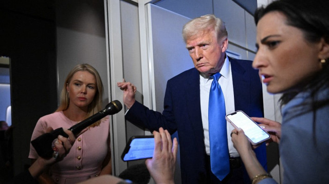 La secrétaire de presse de la Maison Blanche, Karoline Leavitt, écoute (à gauche) le président américain Donald Trump s'adresser aux journalistes à bord d'Air Force One, en route vers la base militaire d'Andrews, le 6 avril 2025.